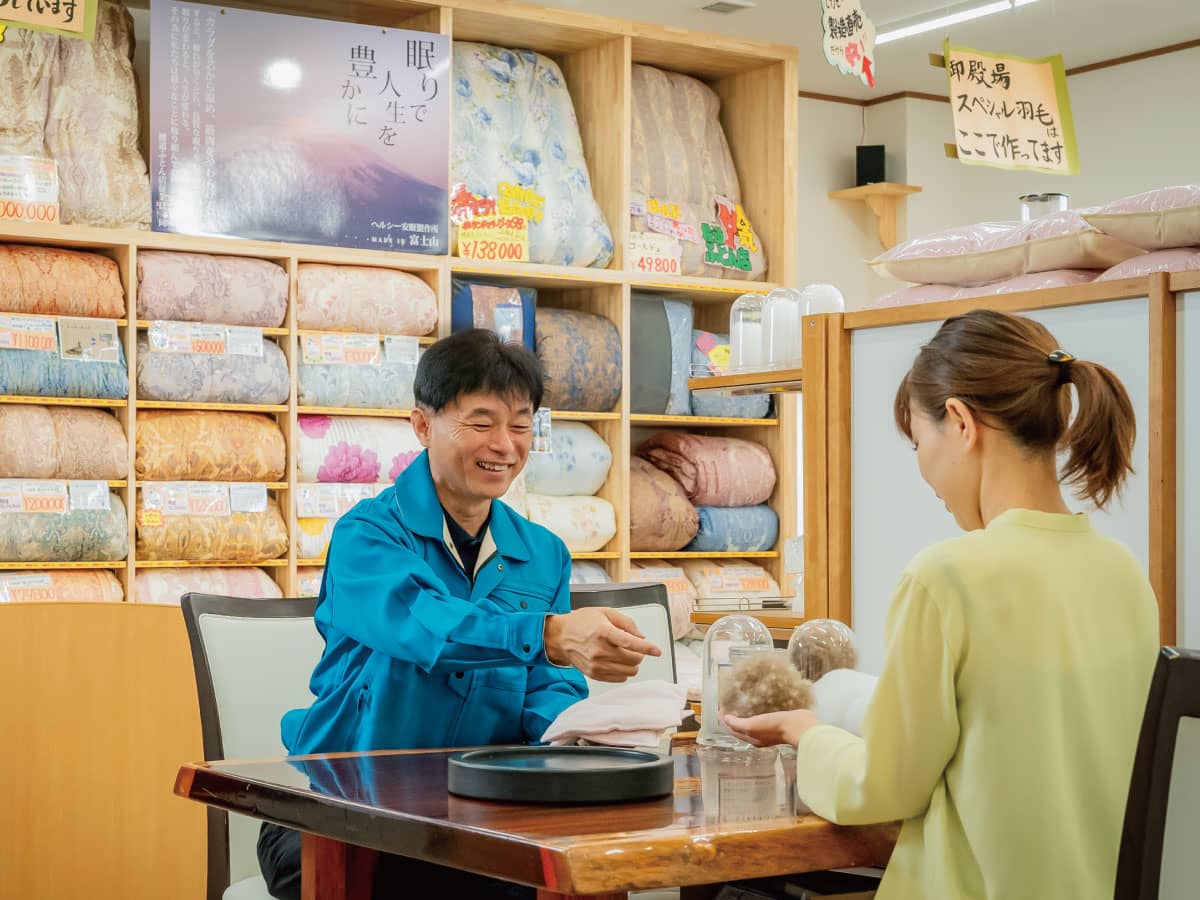 お店で手作り羽毛布団「富士山スペシャル羽毛」で使われている羽毛を手にとって確かめる。